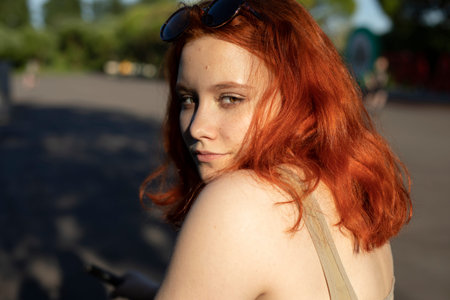 The girl looks dreamy. Red-haired beauty. Teenager in t-shirt. The girl looks over her shoulder. A woman's mysterious look.の写真素材