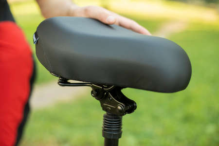 Scooter seat. The hand rests on the seat of the bike. Large comfortable seat in black.の写真素材