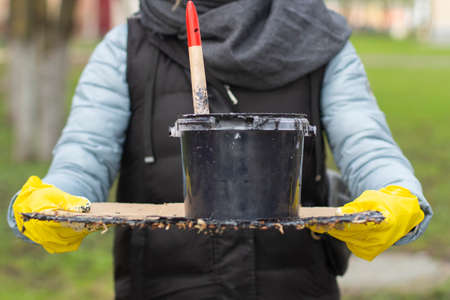 A can of paint in the hands of a woman. The artist starts painting. Preparation of repair workers. Paint brush. Time to serve paint on a tray.の写真素材