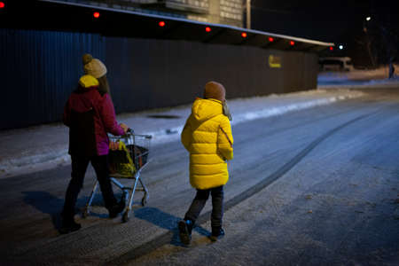 The family goes shopping in winter. Life in the ghetto. Teenagers with a shopping cart on the street.の写真素材