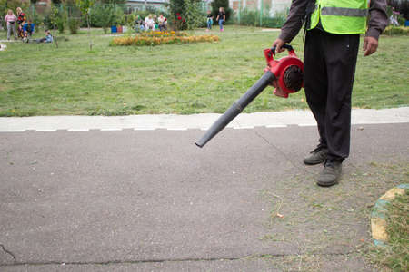 Gardener with a tool. Air turbine in the hand of a worker. Air flow generator for harvesting leaves.の写真素材