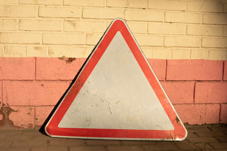 The road sign stands against the wall. The triangle symbolizes traffic. Special symbol for the driver.の写真素材