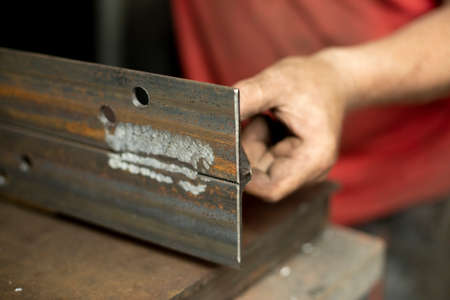 Drilled holes in the metal. Work in a metal workshop. The hand holds a steel blank. A man works in the garage.の写真素材