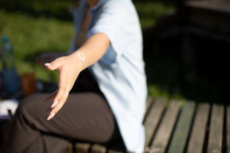 The girl holds out her hand. The girl in the park wants to take something in her hand. Body movement.の写真素材