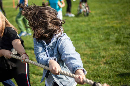The child pulls the rope. Tug of rope. Child's active rest in summer. Sports competition in the yard.の写真素材