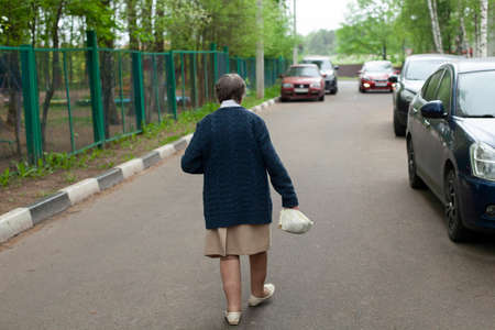The pensioner goes to the shop. A woman in Russia walks through the city. A man walks along the road.の写真素材
