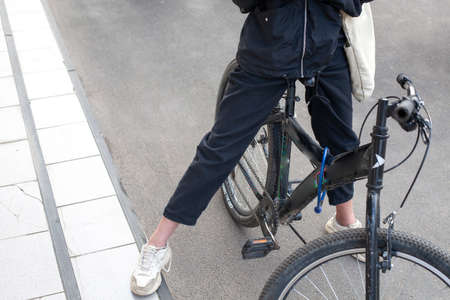 The girl stands on a bicycle. The teenager on the street put her foot on the pedal. The schoolgirl is rolling around the city and resting.の写真素材