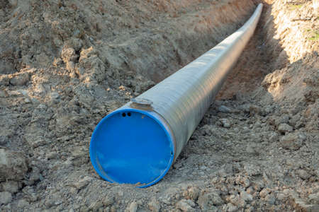 A big pipe for oil. The pipe burrows into the ground. Industrial transport of fuel. Laying communications. Digging into the ground infrastructure.の写真素材