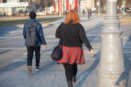 A girl in a red skirt walks through the city. The girl and the guy are walking on the street. Young people explore the city on foot.の写真素材
