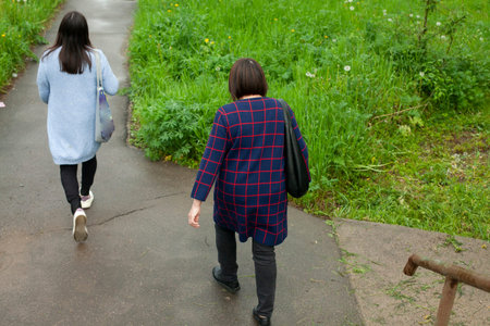 Women are walking along a narrow road. People in the pedestrian zone. Women go to the bus.の写真素材