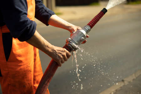 Water hose. The flow of water from the pipe. A man holds a fire hose.の写真素材