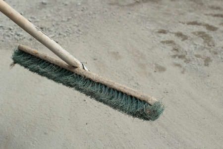 The mop removes dust and sand from the road. Yard cleaning cleaner. A mop with tight bristles and a handle made of wood.の写真素材
