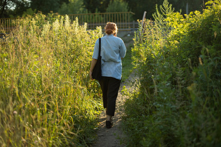 The girl walks through the thickets. A teenager walks in the woods. The woman got lost in the wild.の写真素材