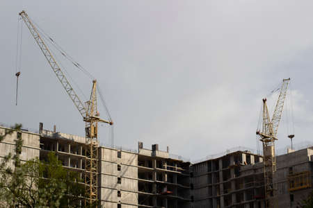 Building a house with a construction crane. Construction of an apartment building. View of the construction of a multi-storey building.の写真素材