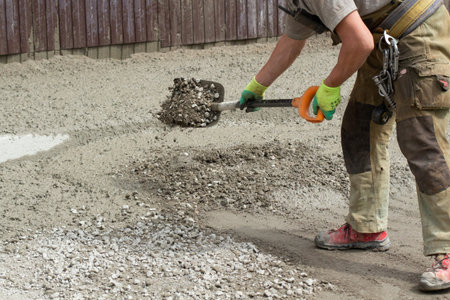 Work with a shovel at a construction site. A worker throws cement and gravel with a shovel. Cleaning...