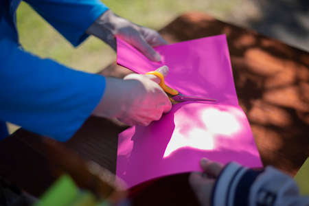 Cutting colored paper. Scissors cut the paper. Creativity with children. Master class on the street.の写真素材