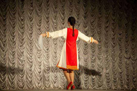 A girl in a folk costume in Russia. Performance on stage. Choreographic lesson. The girl is dancing in a long sundress.の写真素材