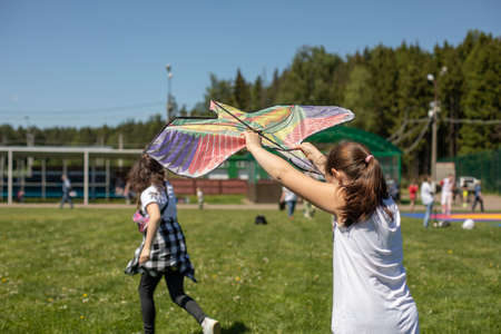Children fly a kite. Two girls are trying to launch a bird figure hovering in the wind.の写真素材