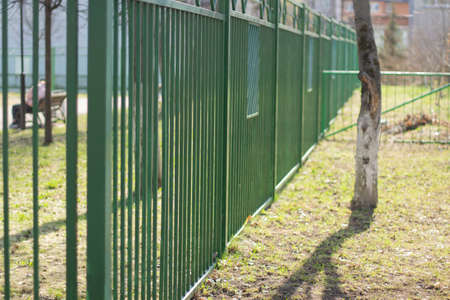 Green fence. Fencing around the territory. Metal fence on the street.の写真素材