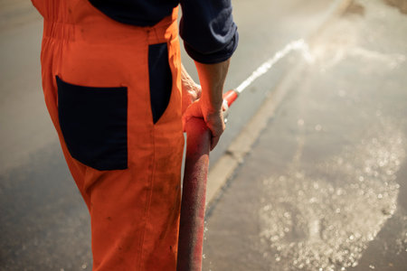 Water hose. The flow of water from the pipe. A man holds a fire hose.の写真素材