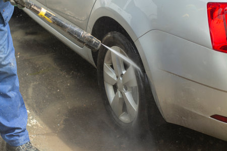 The car is washed at the car wash. Washing the car from dirt. High pressure water spraying equipment for washing car surfaces.の写真素材