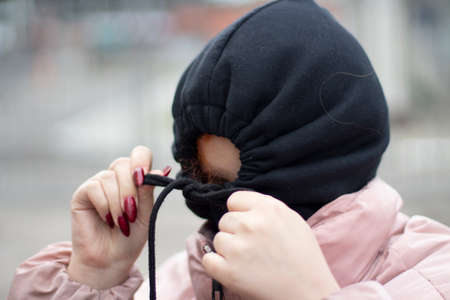 The girl hid in the hood. Girl in a black hood. The schoolgirl hid from people. Self-rejection. The man is depressed. Reluctance to communicate.の写真素材