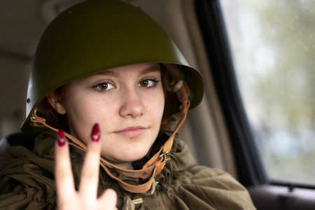 A military helmet of the Second World War on the head of a soldier. Restoration of the image of a soldier in Russia. A girl in a military uniform.の写真素材