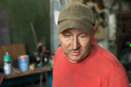 Portrait of a worker in a workshop. Dad's in the garage. A man of labor. A man of age in Russia. A worker in a cap.の写真素材