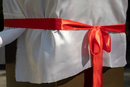 Red fabric bow. Red ribbon on a white cloth. The opening of the monument in detail.の写真素材