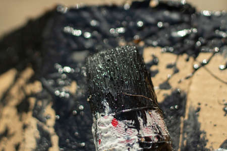 Brush with black paint. Painting with a brush. A lot of paint on the cardboard.の写真素材