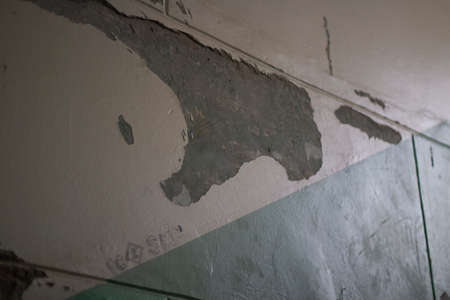 Wall with fallen paint. Wall at the entrance of a residential building. It is dark indoors.の写真素材