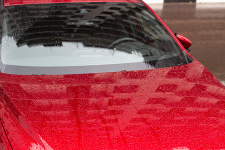 Red car in the parking lot. Car surface. Wet car after rain. Details of the car.