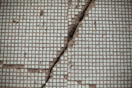 The texture of the collapsed tiles. The tiles on the wall cracked and collapsed. An old wall with broken tiles.の写真素材
