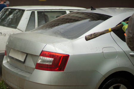 Car wash. The car is washed under the pressure of a jet of water. Using a water spray to wash off dirt from the surface of the car.の写真素材