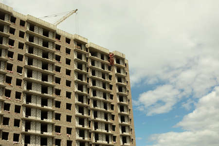 Building under construction in the city. Construction of a multi-storey building. Construction works on the street. Apartment unfinished building in Russia.の写真素材