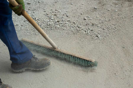 The mop removes dust and sand from the road. Yard cleaning cleaner. A mop with tight bristles and a handle made of wood.の写真素材
