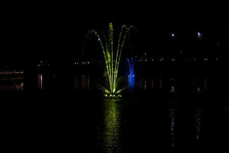 Colored fountain at night. Colored fountain on the pond. The streams of water are highlighted with a colored fan.の写真素材