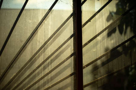 Muddy window with lattice. An old dirty window in the production room. Steel bars protect the window opening.の写真素材