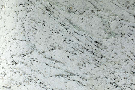 The texture of white stone with inclusions of black dots and lines. The surface of the rock is in detail. Decorative stone in natural light.の写真素材