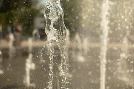 City fountain. Splashes of water on the square. Summer freshness from water jets.