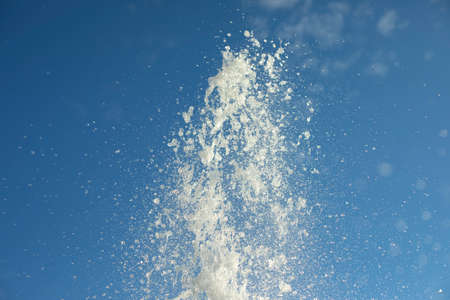 Splashes of water in the air. A jet of fantan on the background of the sky. Small drops fly to the sides.の写真素材