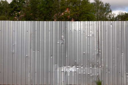 Fence made of steel. Simple fencing. It is protected by a metal fence. Crutty material. A high fence hides what is behind it.の写真素材