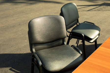 Black chairs stand outside. Office furniture in black. Sitting in sunlight.の写真素材