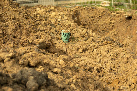 Dug up land at a construction site. Dug up soil in the city. The green pipe sticks out of the ground.の写真素材