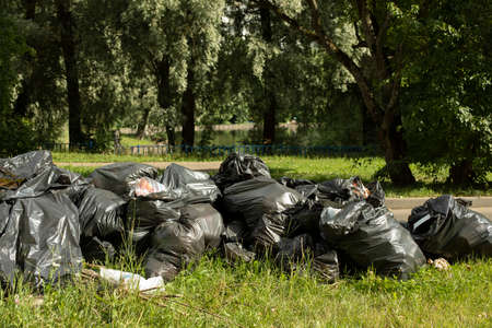 Garbage bags on the street. Black bags of waste in the park. Black palitylene bag.の写真素材