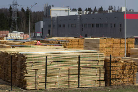 Building materials in a street warehouse. The boards are stacked. Product prepared for loading. Lumber behind the fence.の写真素材