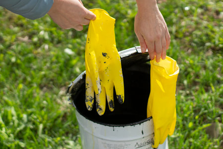 Yellow gloves and a bucket of paint. Working gloves in hand. The beginning of repairs in the house. Protect your hands from paint.の写真素材