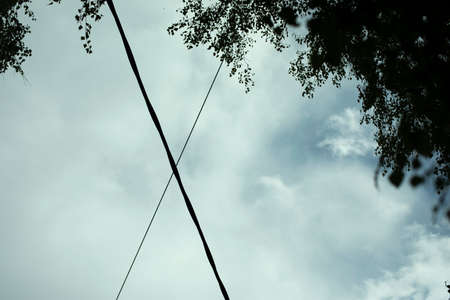 A cross of wires in the sky. Background intersection of stretched cables with electricity. A sign in the sky.の写真素材