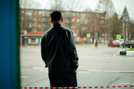 A man in a black jacket is waiting by the road. Unknown guy. Waiting for a meeting. The Russian reality of the common man on the street.の写真素材