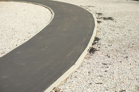 New asphalt road in the park. Narrow park path for cyclists. Repaired road surface.の写真素材